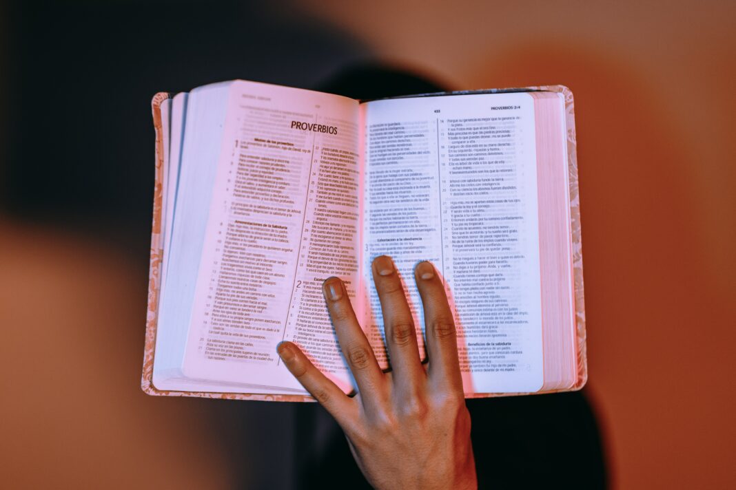 Reflexões bíblicas com uma mão segurando uma bíblia sagrada aberta